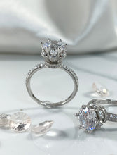 Load image into Gallery viewer, The timeless six-prong setting offers a flawlessly engineered facet to the head of the ring that radiates a stunning reflection comparable to one of the world’s most expensive diamonds. Lined along the upper shank are cubic zirconia accents stones, pointing your attention back to the glorious head. Material: 925 Sterling Silver, Cubic Zirconia Design: Classic Weight: 2.9g
