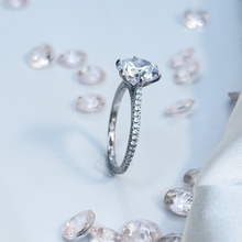 Load image into Gallery viewer, The stunning slender shank is balanced by the large brilliant round zirconia stone head that radiates light comparable to an expensive diamond. Offering a bold and sophisticated look are the cubic zirconia accent stones lined perfectly to lead the eyes to the head of the ring. Material: 925 Sterling Silver, Cubic Zirconia Design: Luxurious Weight: 2.8g.